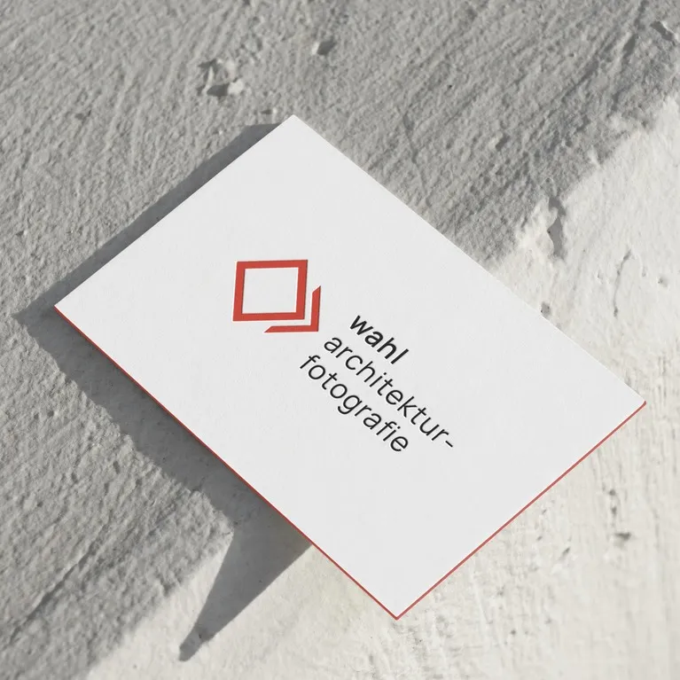 Auf einer Visitenkarte mit strukturierter weißer Oberfläche sind ein rotes quadratisches Logo und der Text „wahl architektur-fotografie“ in schwarzen Kleinbuchstaben abgebildet.